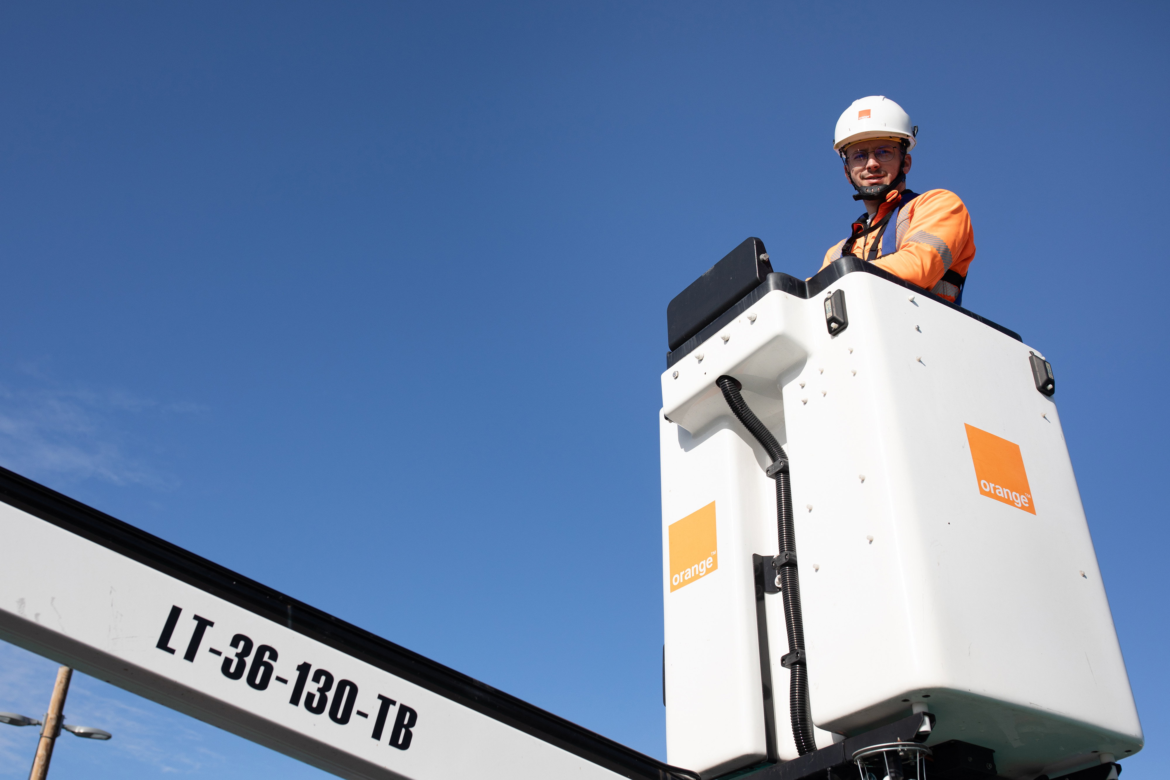 An Orange employee on a crane installing an antenna