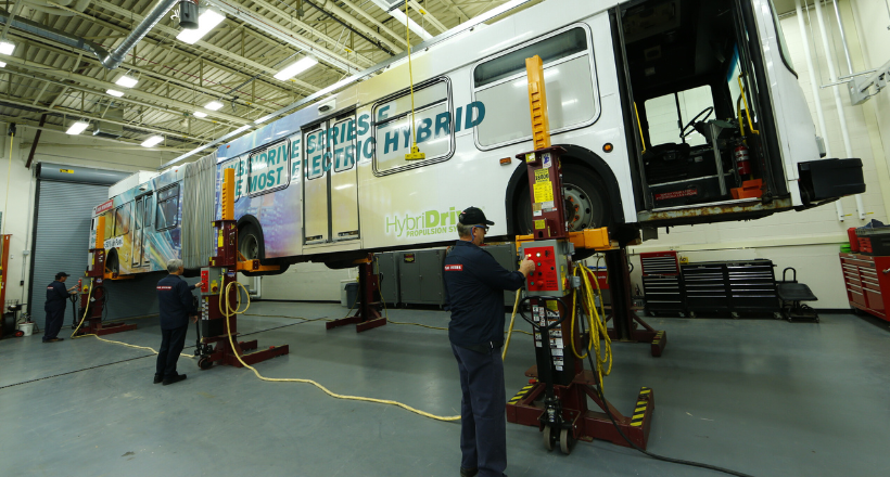 Two BAE Systems employees working on a hybrid-electric bus.