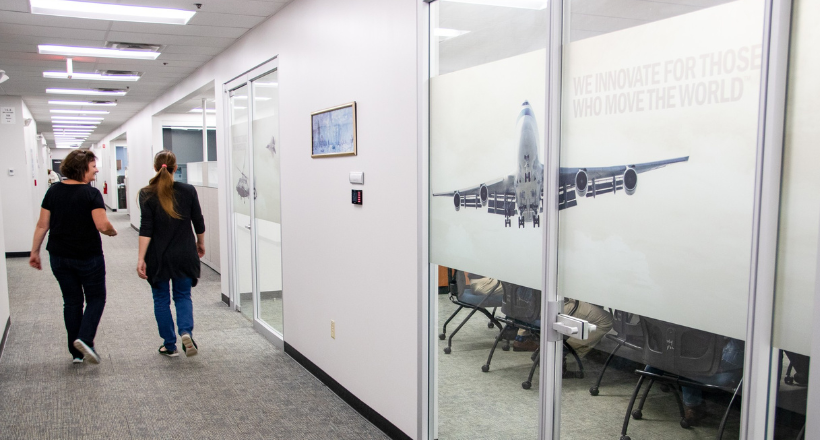 Two employees walking down a hallway in the endicott office. 