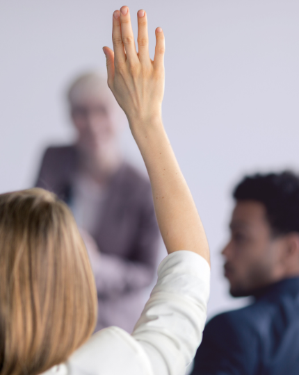A female raises her hand to ask a question.
