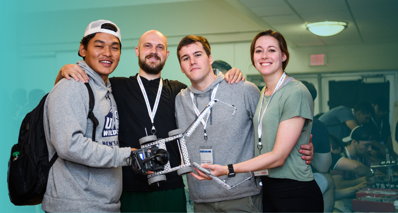 Four leadership development program participants at the leadership development conference posing with their robot they designed for a competition. 