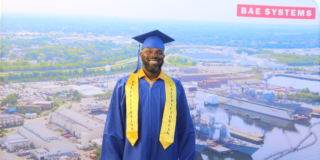 Antoine, a BAE Systems employee, smiling for a photo in his cap and gown after graduating from the Ship Repair Apprentice Program.