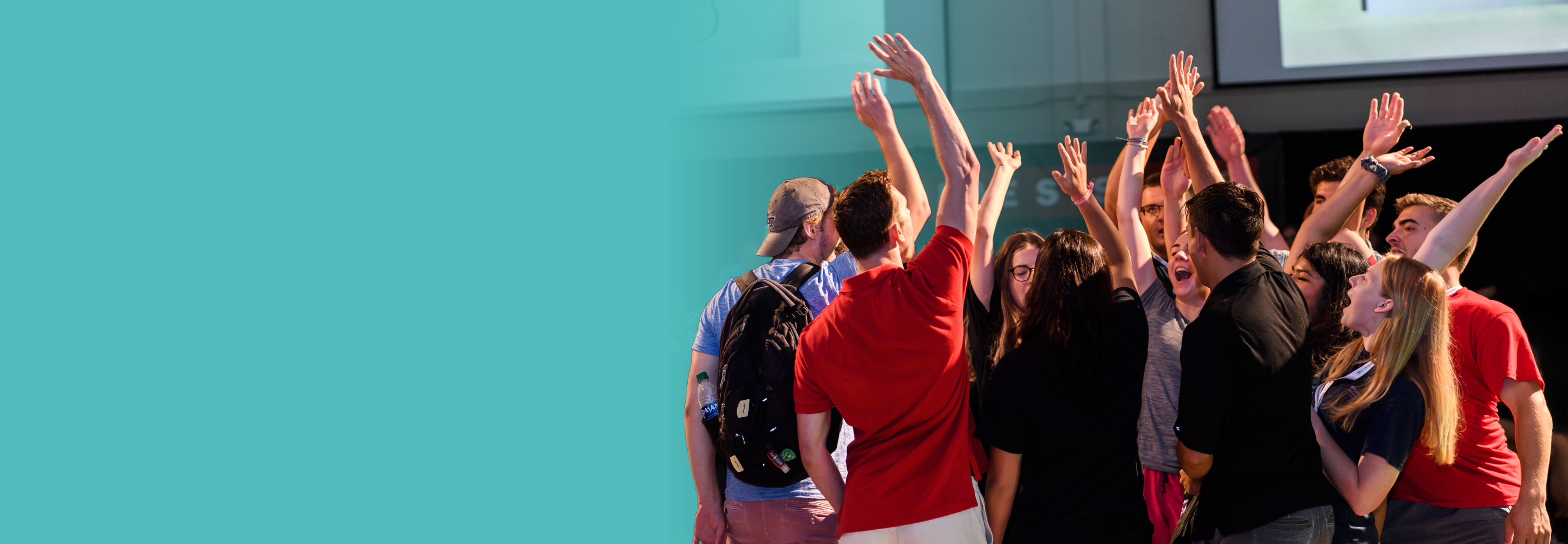 A group of leadership development program participants raising there hand after a team cheer at the annual leadership development conference.