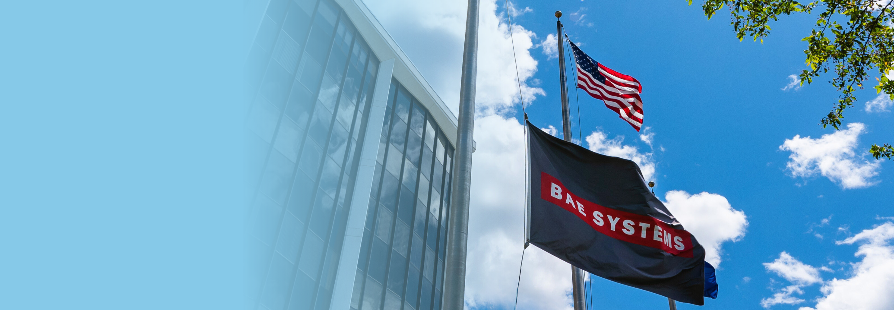 BAE Systems flag flies in the wind and underneath an American flag. Text of graphic: Alumni