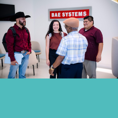 Four BAE Systems employees converse in an office lobby.