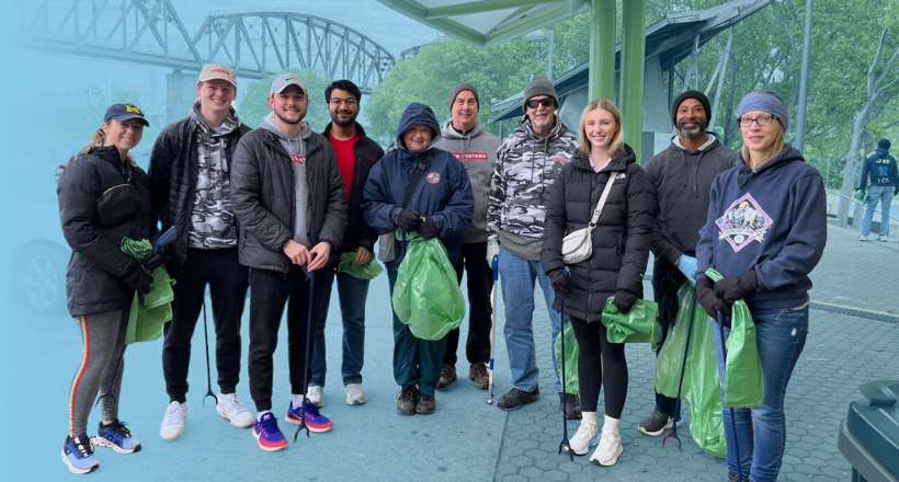 A group of BAE Systems employees holding trash bags after a river clean up.