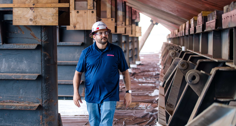 A BAE Systems employee walking next to a docked vessel.
