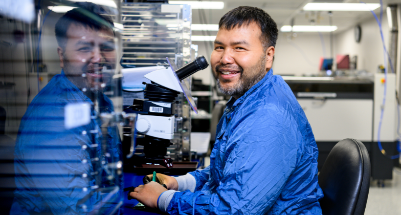 A technician smiling for a photo in the manufacturing facility. 