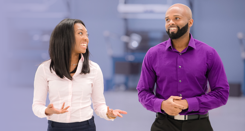 Two co-workers chatting at work as they walk..