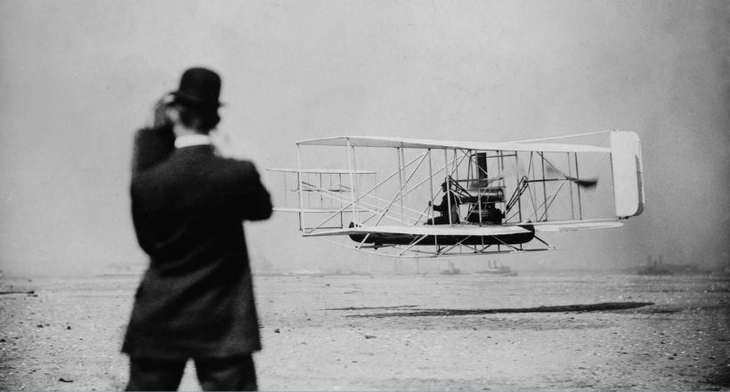 Vintage photo of Wilbur Wright taking off for a flight in an early airplane. 