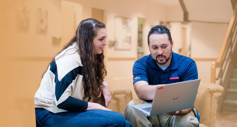 A senior BAE Systems employee teaching a younger employee something on this laptop. 