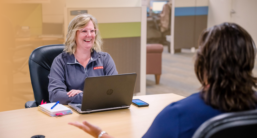 Two intelligence and security sector employees have a conversation in a BAE Systems office. 