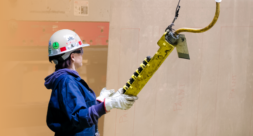 A ship repair employee uses a remote lower some heavy equipment.