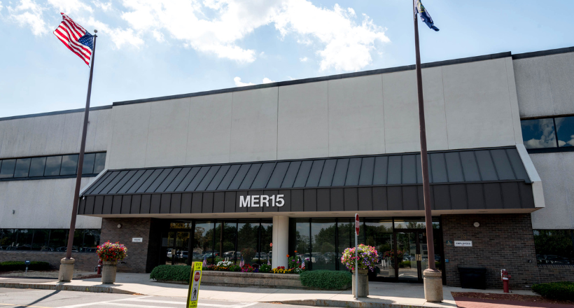 American flag flying above a BAE Systems flag on a flag pole.