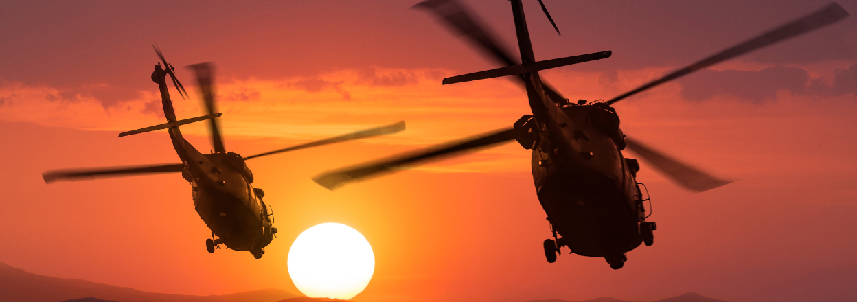 Two U.S. Army helicopters flying during sunset.