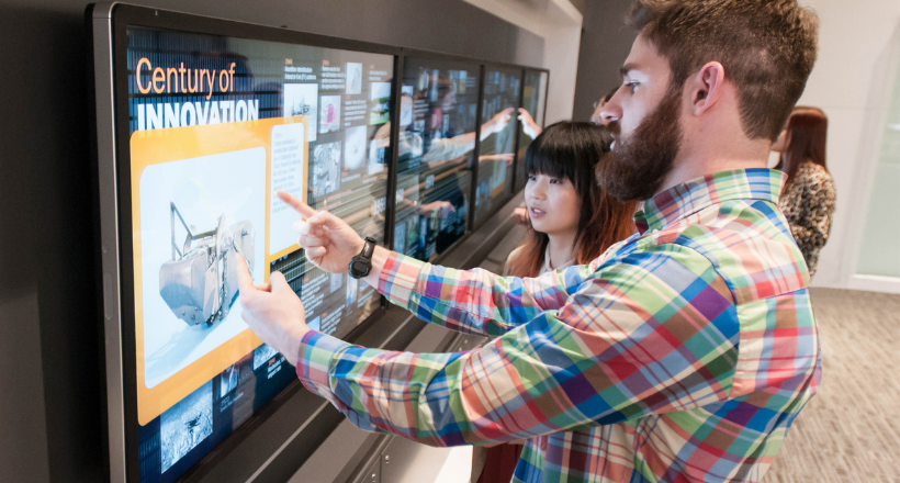 Two early career professionals working on a touch screen.