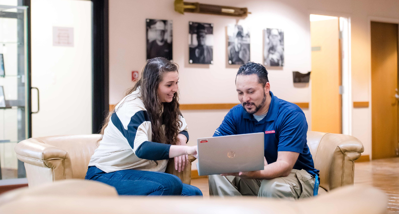 A mentor showing a mentee something on the computer in the lobby of Jacksonville Ship Repair.
