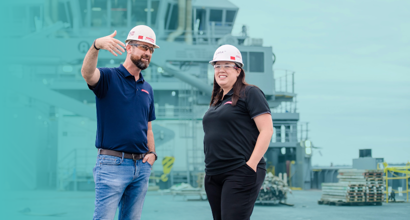 David and Sarah, two members of our ship repair team stand on a navy vessel and converse.