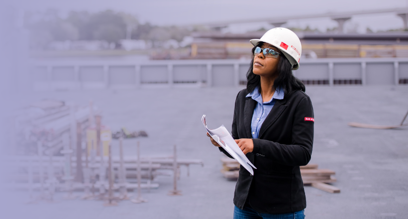 Nakia, an operations manager, stands on a Navy vessel with a clip board as she surveys some equipment.
