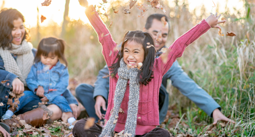 A family playing in the outdoors during the fall.