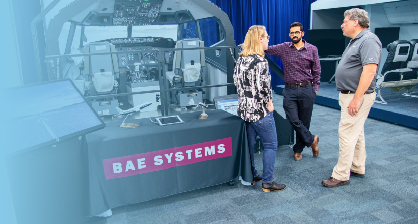 Three employees standing in front of aviation technology having a discusiion. 