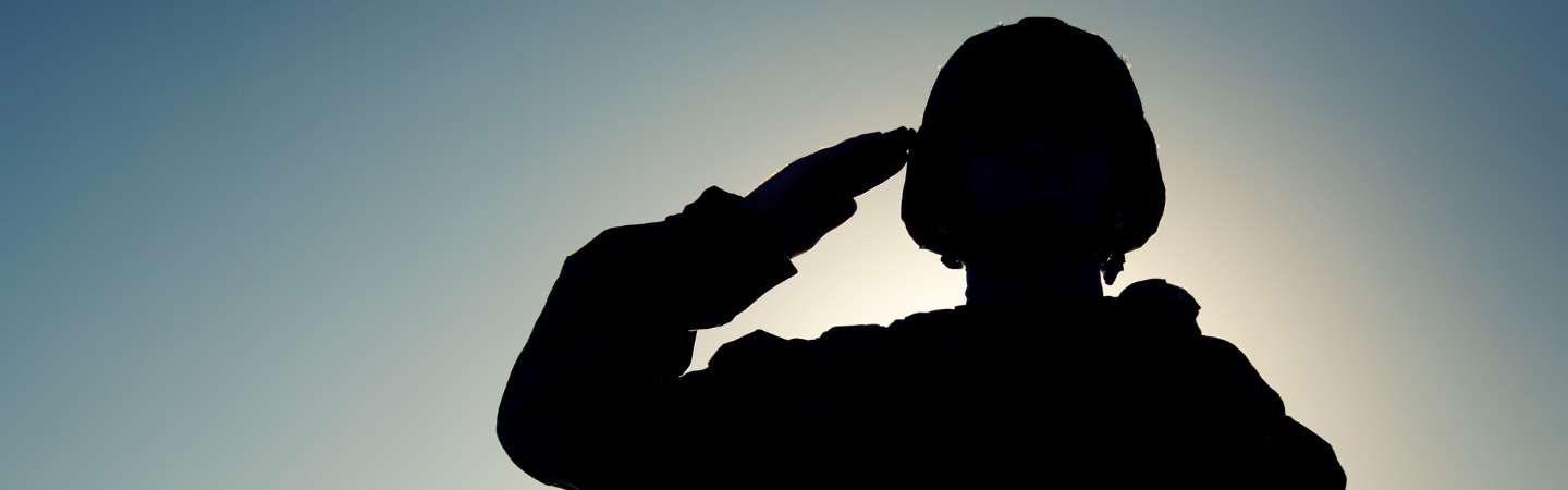 A close up silhouette of a military service member saluting.