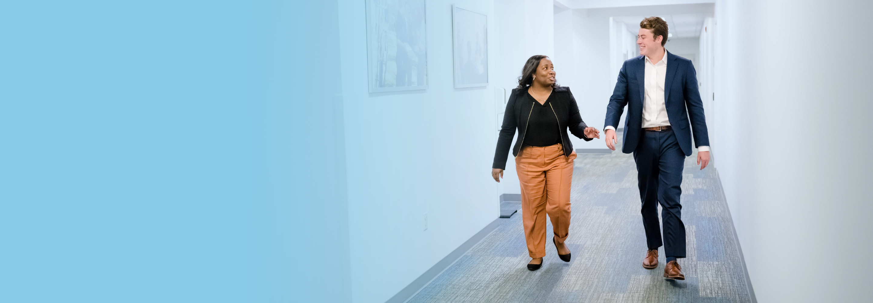 Graphic featuring Ronda and Chris, members of the intelligence and security team. They walk down a hallway in the office in a discussion.