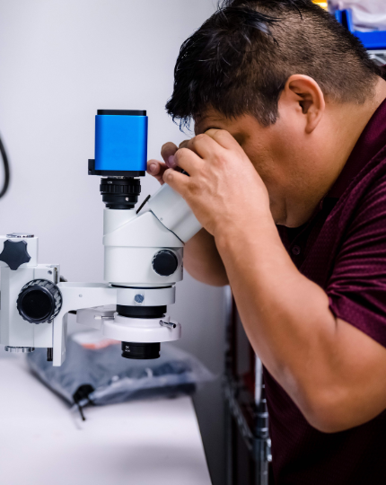 Jose, an electrical engineer, looks through a microscope.