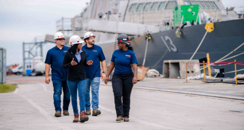 Four Jacksonville Ship Repair employees walk through the ship yard.