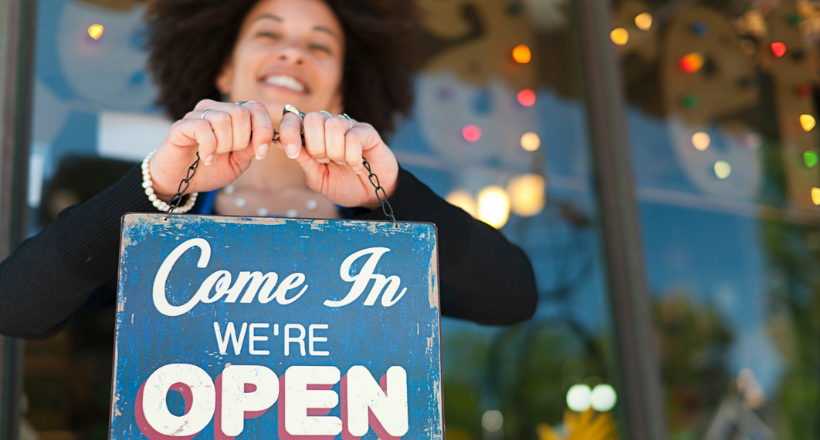 Small business owner holding a "we're open" sign.