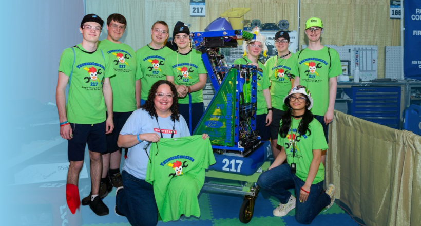 A BAE Systems mentor poses for a photo with the FIRST robotics team she helped coach.
