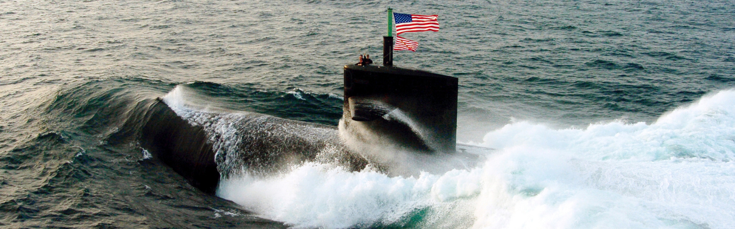 A Military submarine driving near the surface of the water with American Flags flying in the wind.