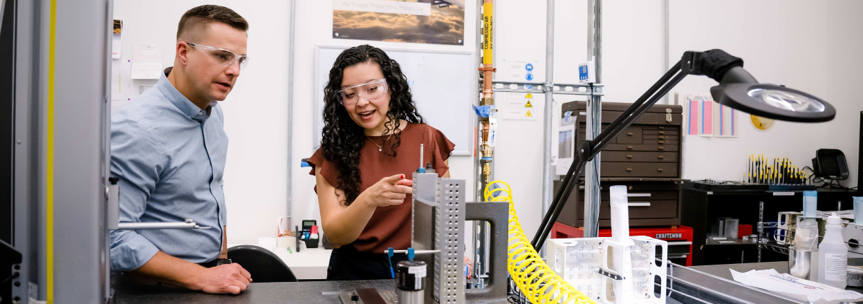 Two employees talking about a piece of equipment in the manufacturing floor.