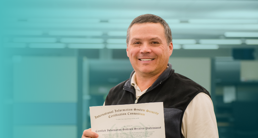 A BAE Systems cybersecurity professional posing with his CISSP certifcation.