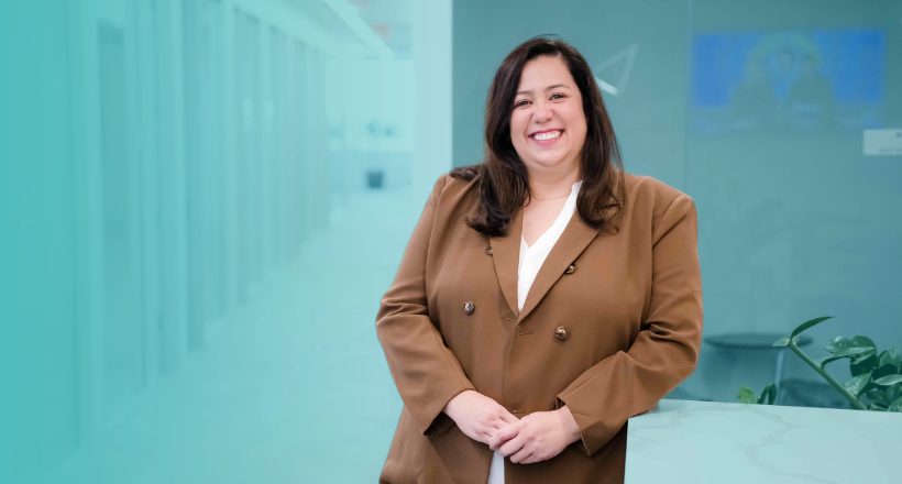 Amy, director of talent management, smiles and stands in the office hallway.