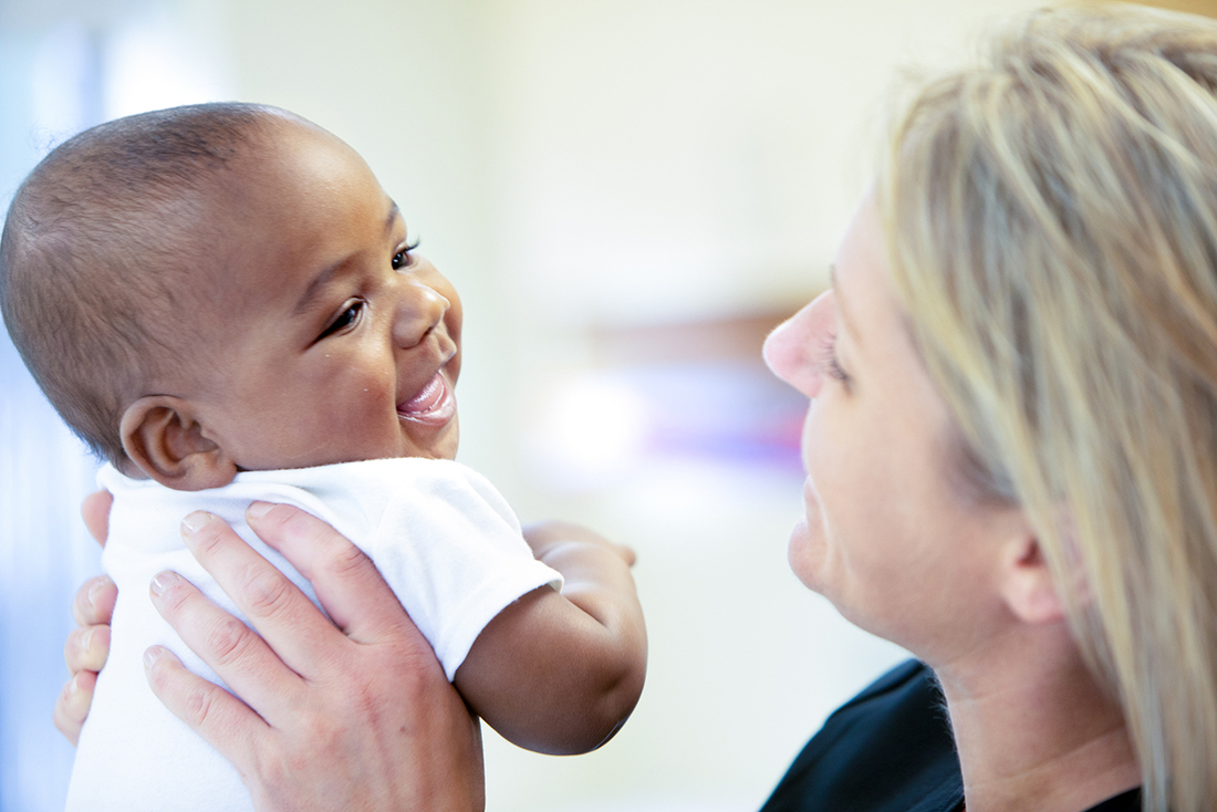 Adult holding an infant in an indoor care environment.