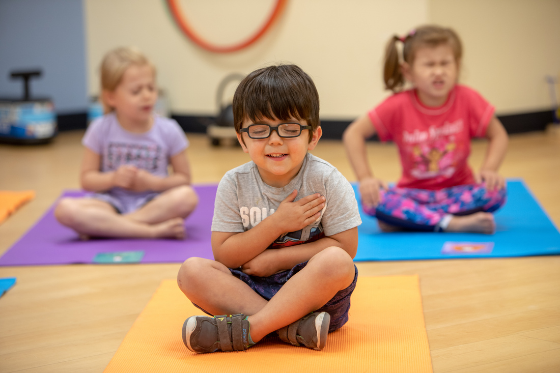 Children seated on yoga mats during a group activity.