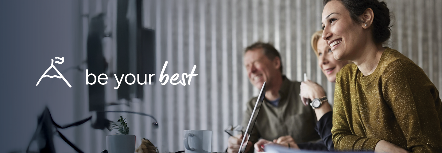 A diverse group of professionals smiles while sitting at a table, with the words "be your best" and a mountain icon on the left.