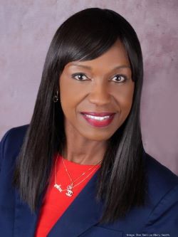 Headshot of Odesa Stapleton in a red shirt blue blazer