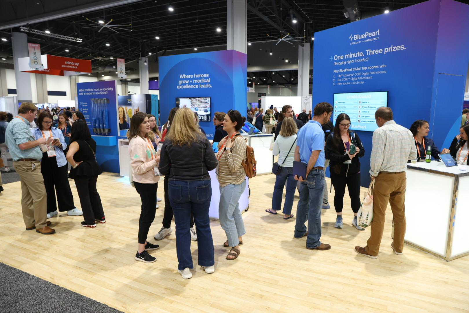 A crowd of people enjoy each others' company at the BluePearl booth at IVECCS 2026.