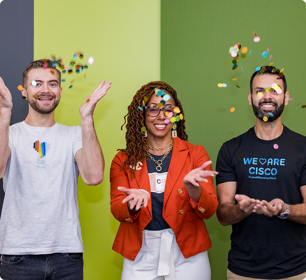 Two men and a woman tossing confetti in the air and smiling.