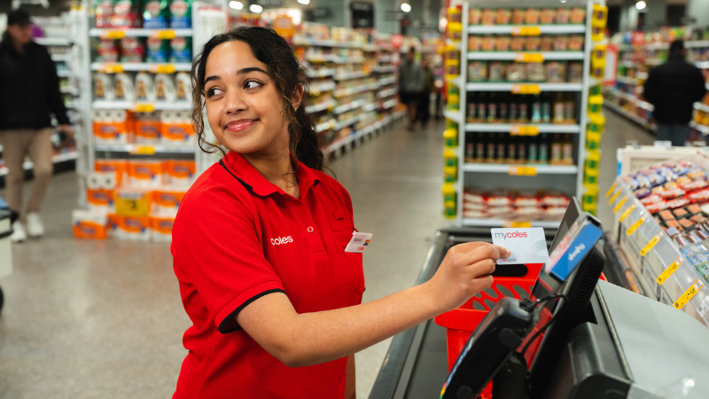 A young female team member using their mycoles discount card in the self checkout