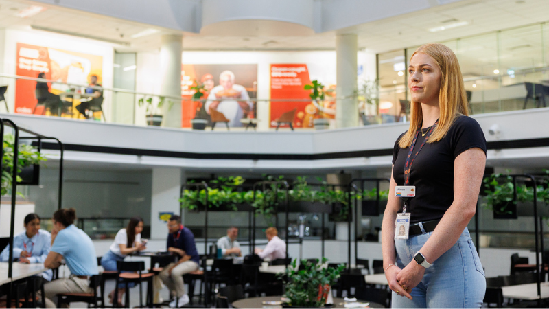 A female graduate standing in the middle of Coles Store Support Centre. 