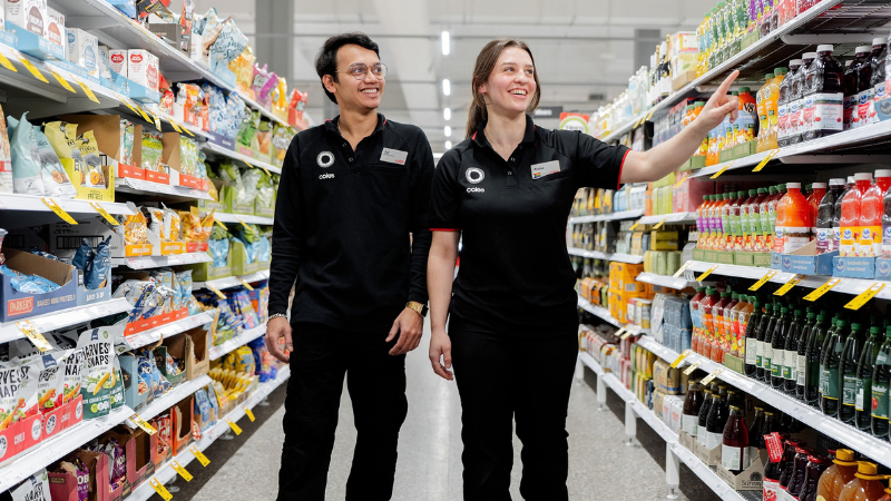 Coles team members walking through a supermarket aisle during a shift