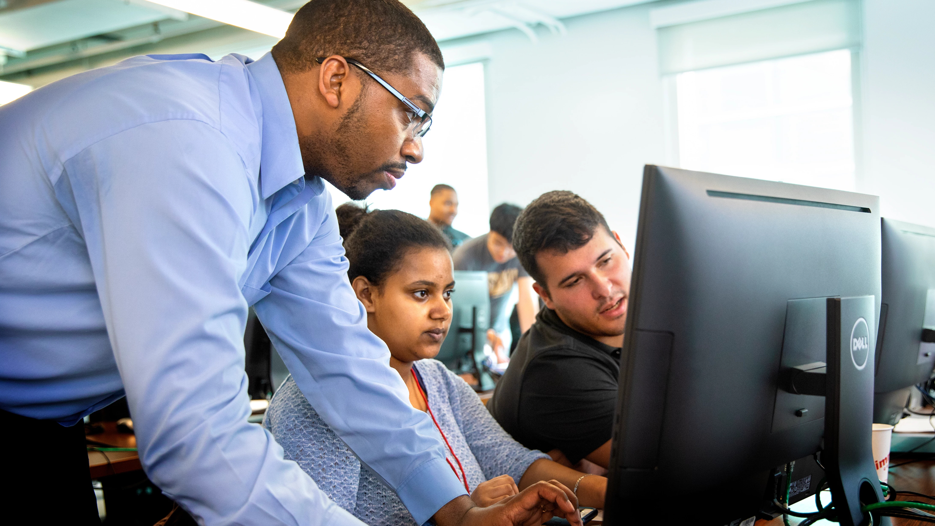 Black instructor helping woman at computer