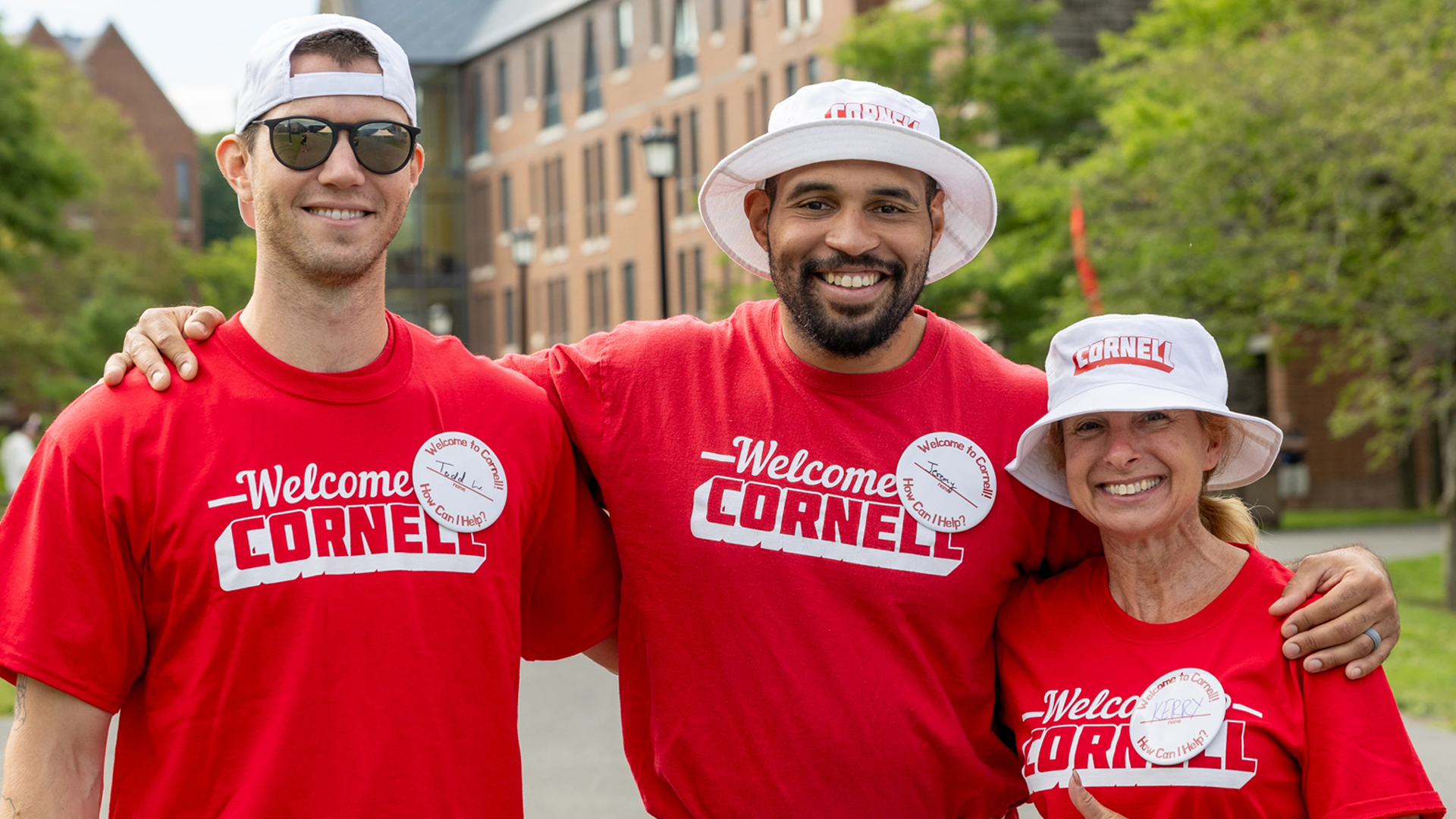 three diverse volunteers wearing Cornell shirts & swag