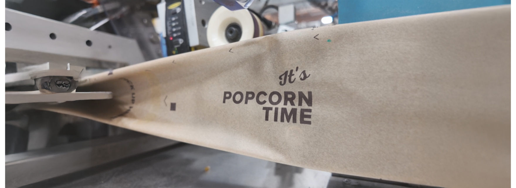 Bag that says It's Popcorn Time running through a machine