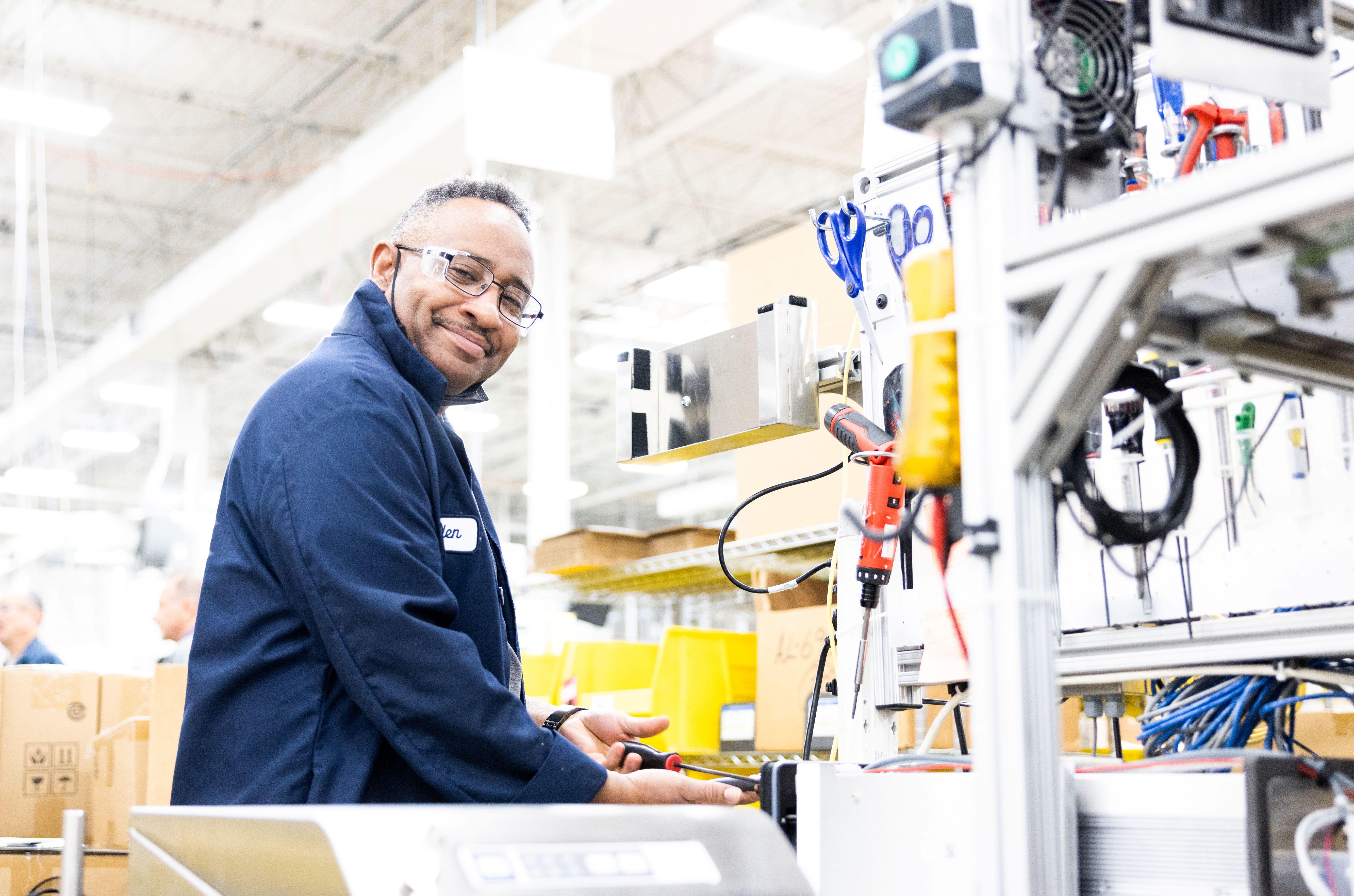 A manufacturing worker smiling at his work station