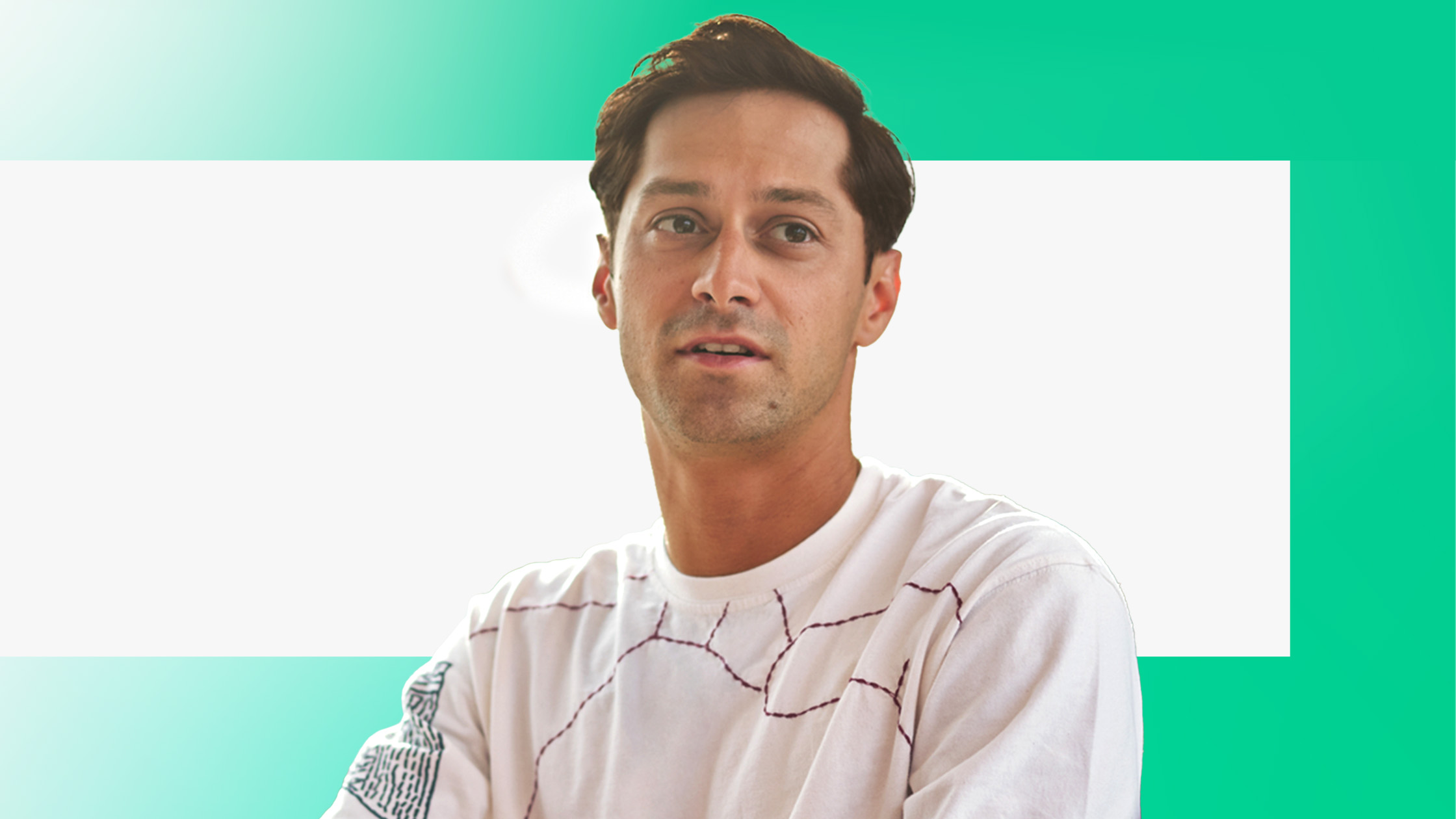 A man with short dark hair wearing a white shirt with abstract lines stands in front of a bright green and white background.