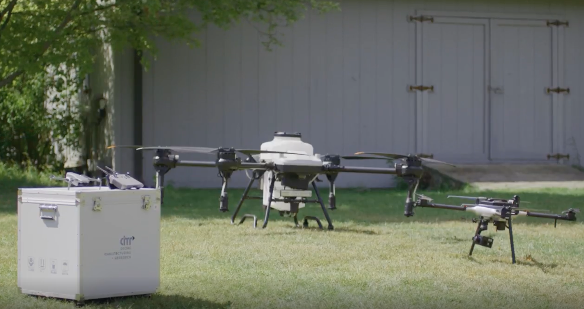 Large industrial drone with mounted payload resting on grass, prepared for professional aerial operations.